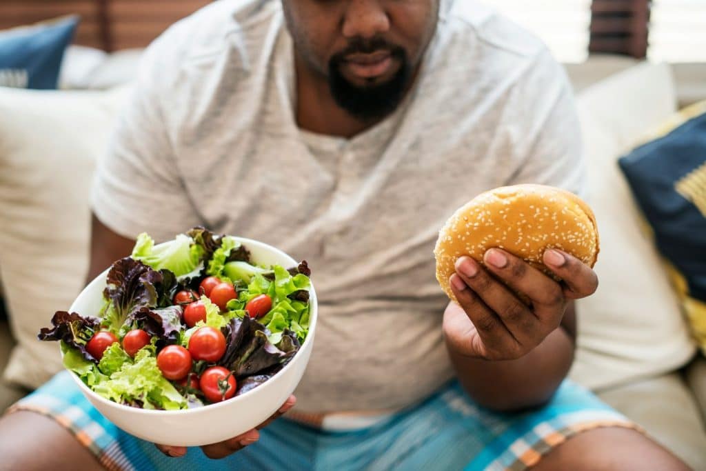 A man choosing between a burger and a salad.