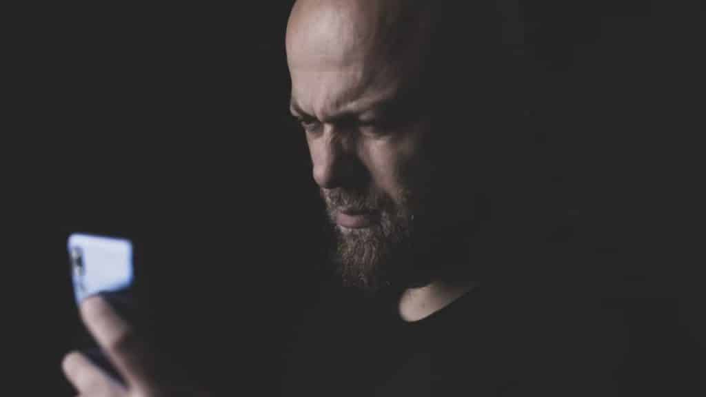 Man holding his phone looking frustrated during texting.