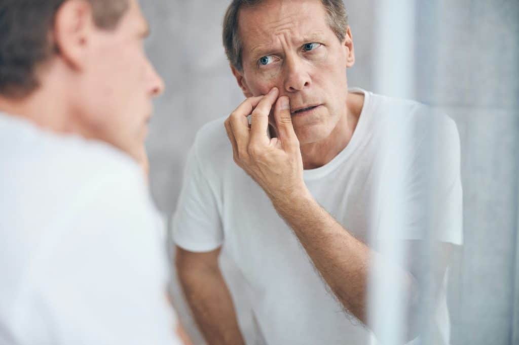 A man spotting a pimple on his face.