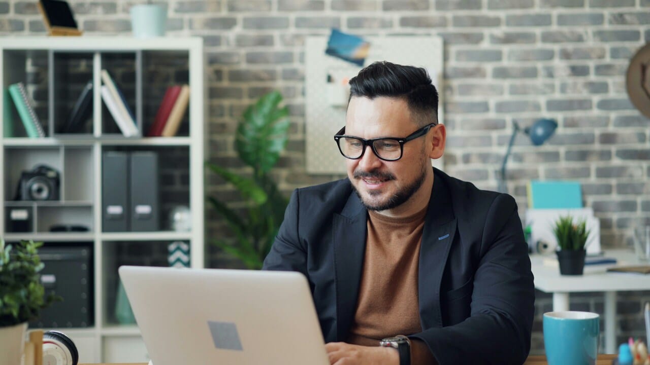 A man looking at his laptop while smiling.