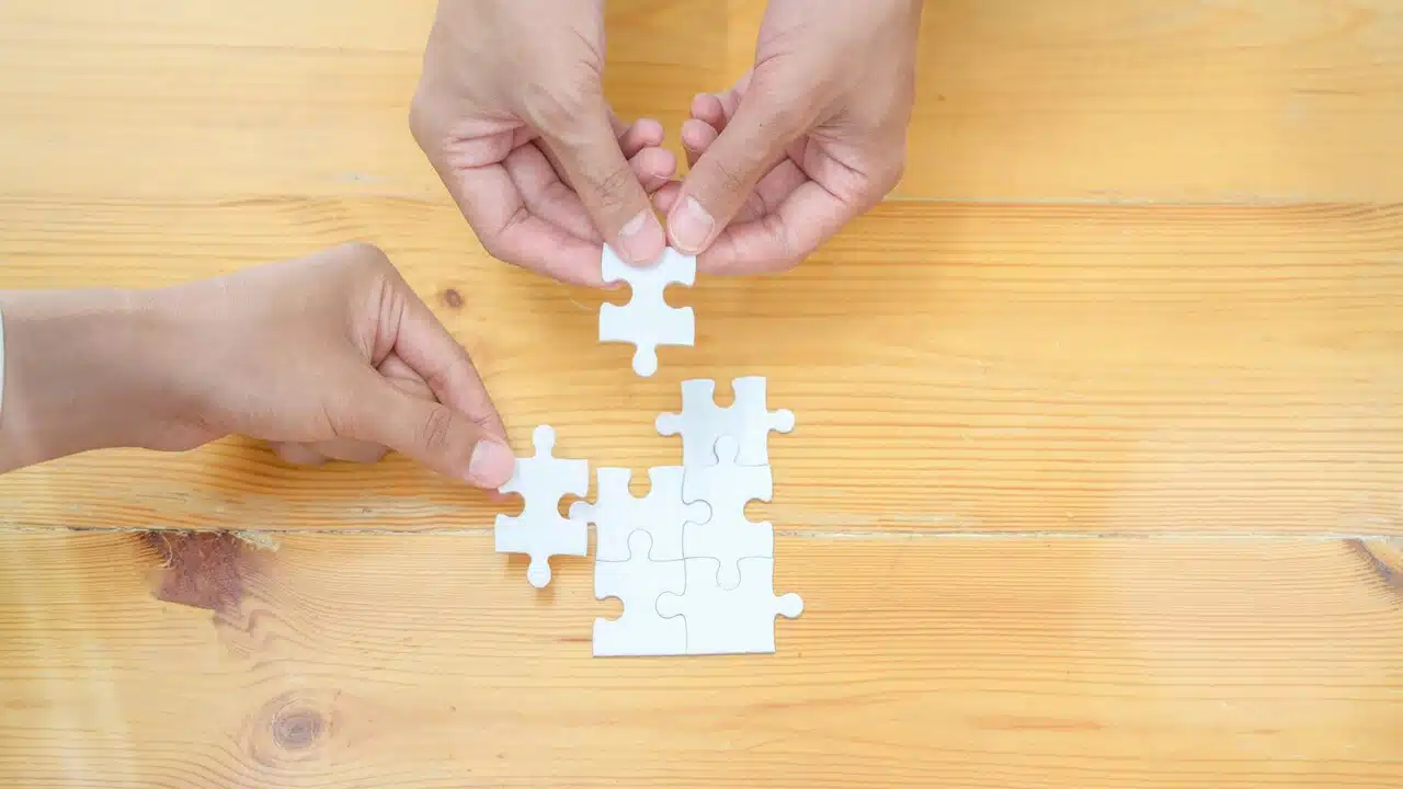 Two hands assembling a jigsaw puzzle.