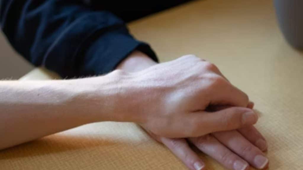 Hand of a man offering a sincere apology while holding his partner’s hand.
