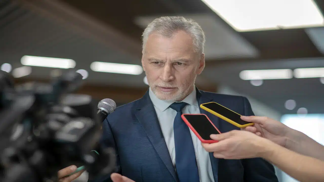 A man in a suit holding a press conference.