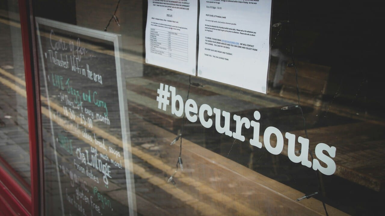 A window sign saying “be curious”.