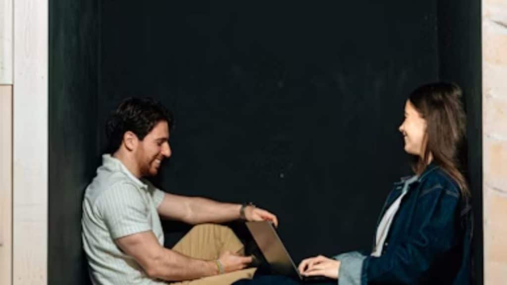 Couple sitting together, smiling and reflecting after resolving an argument.