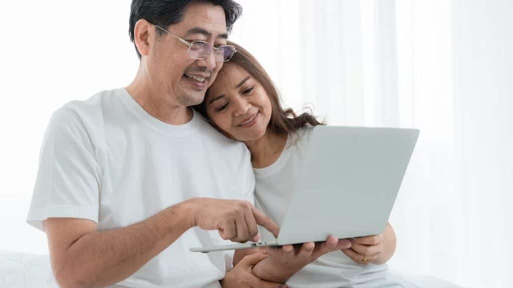  Man checking his personal bank account while partner reads nearby.