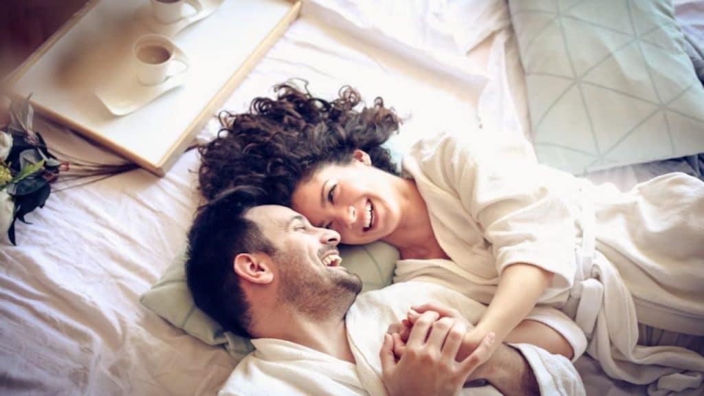 Couple happily cuddling each other in bed