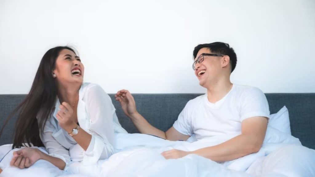 Man and woman laughing together in bed in a moment of genuine fun