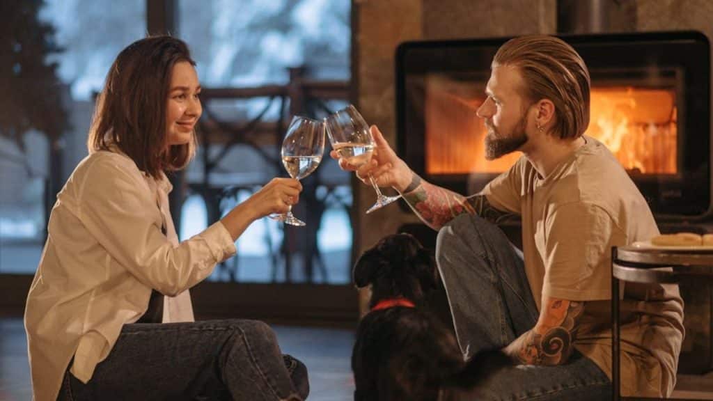 Couple talking and drinking wine by a fireplace in a cozy setting
