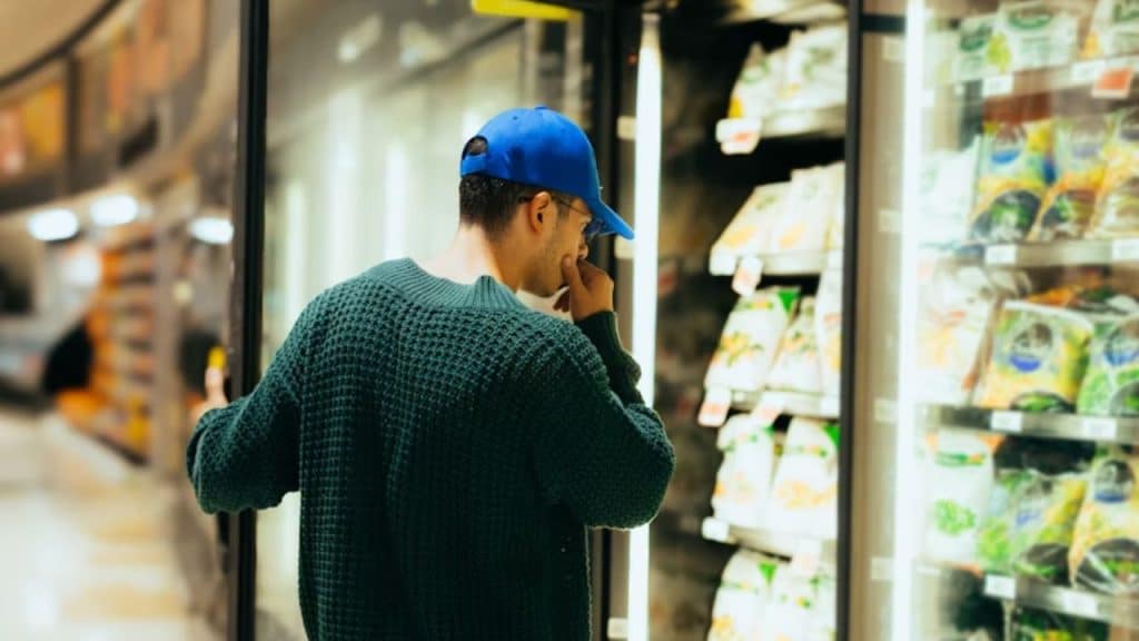 Man reconsidering an emotional purchase before buying in a store.