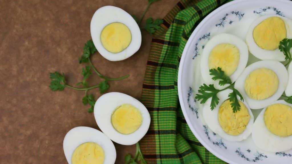 A plate of halved hard-boiled eggs garnished with parsley on a checkered cloth.