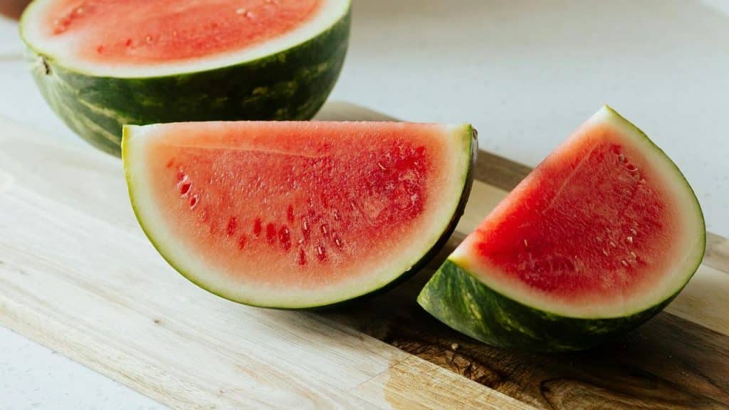 A wooden cutting board holding triangular slices of ripe red watermelon.