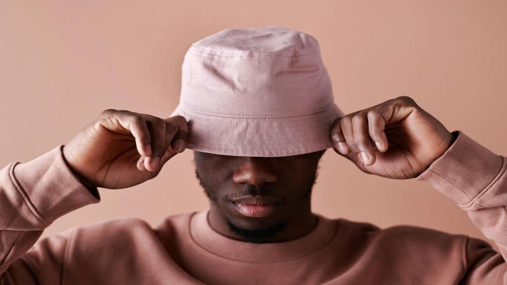 A man wearing a pink sweatshirt and floppy hat.