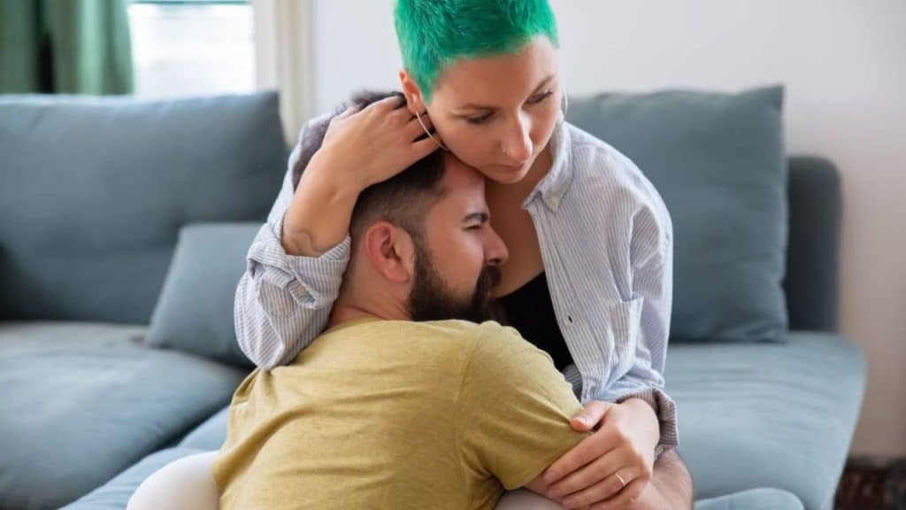 Man leaning on his partner for emotional support at home.