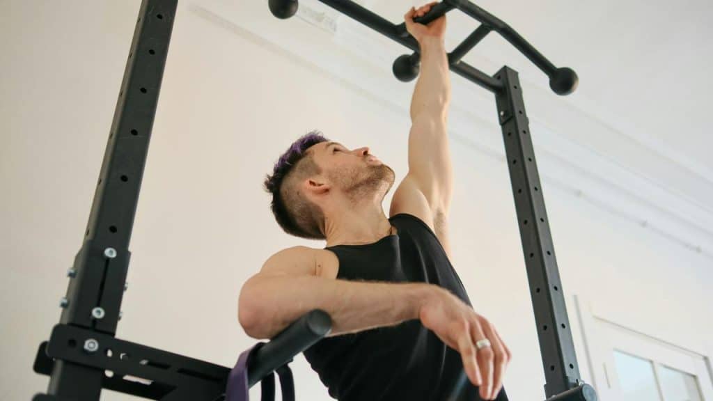 A man reaching up to grab a pull-up bar.