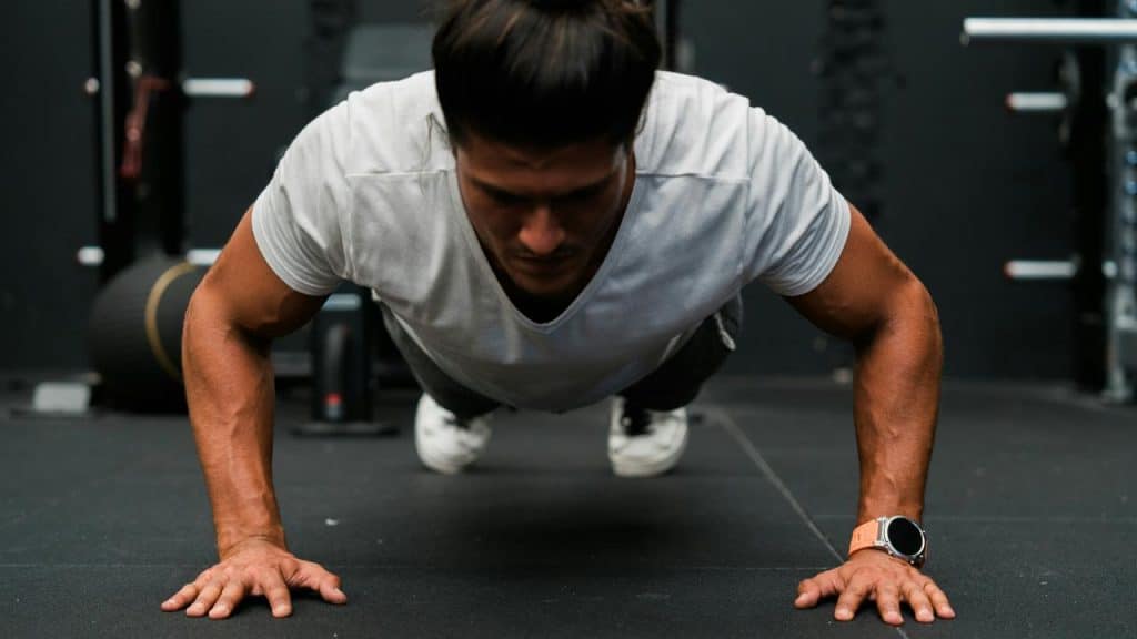 A man doing a push-up on a gym floor.