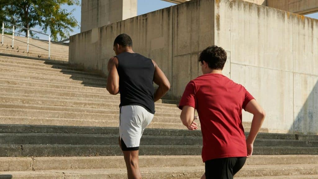 A pair of men running up concrete steps outdoors.