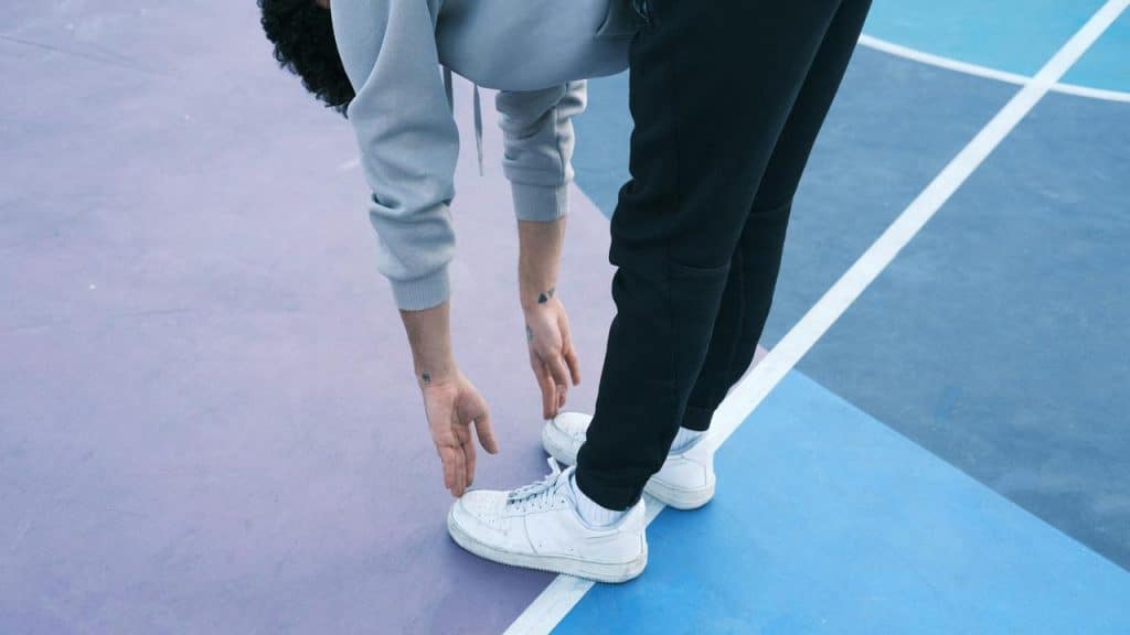 A person touching their toes on a colorful outdoor court.
