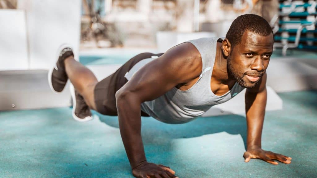 A man doing a raised-leg push-up outdoors.