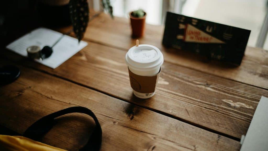 A takeaway coffee cup on a wooden table.