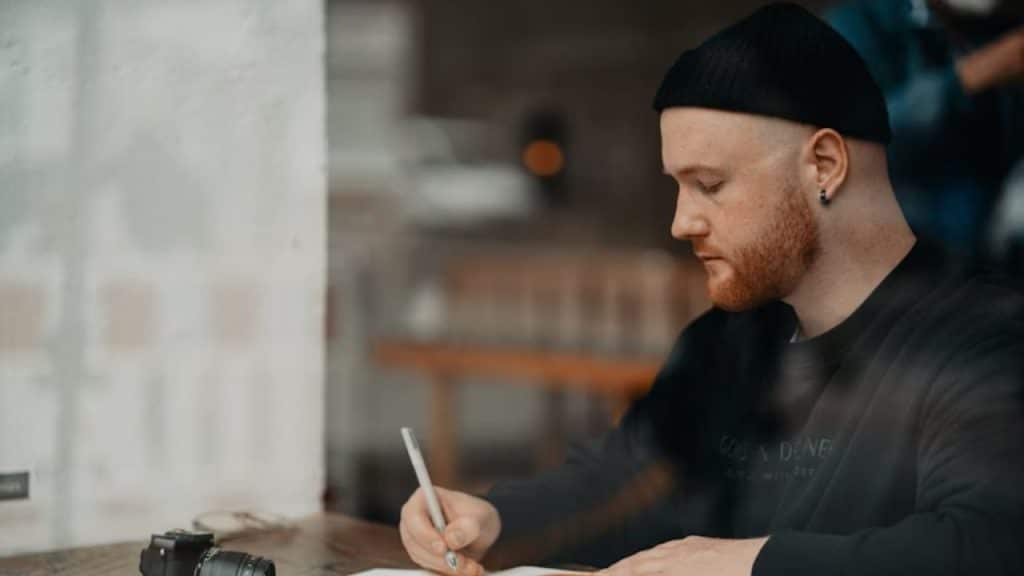 Man sitting alone, writing in a journal during emotional reflection.
