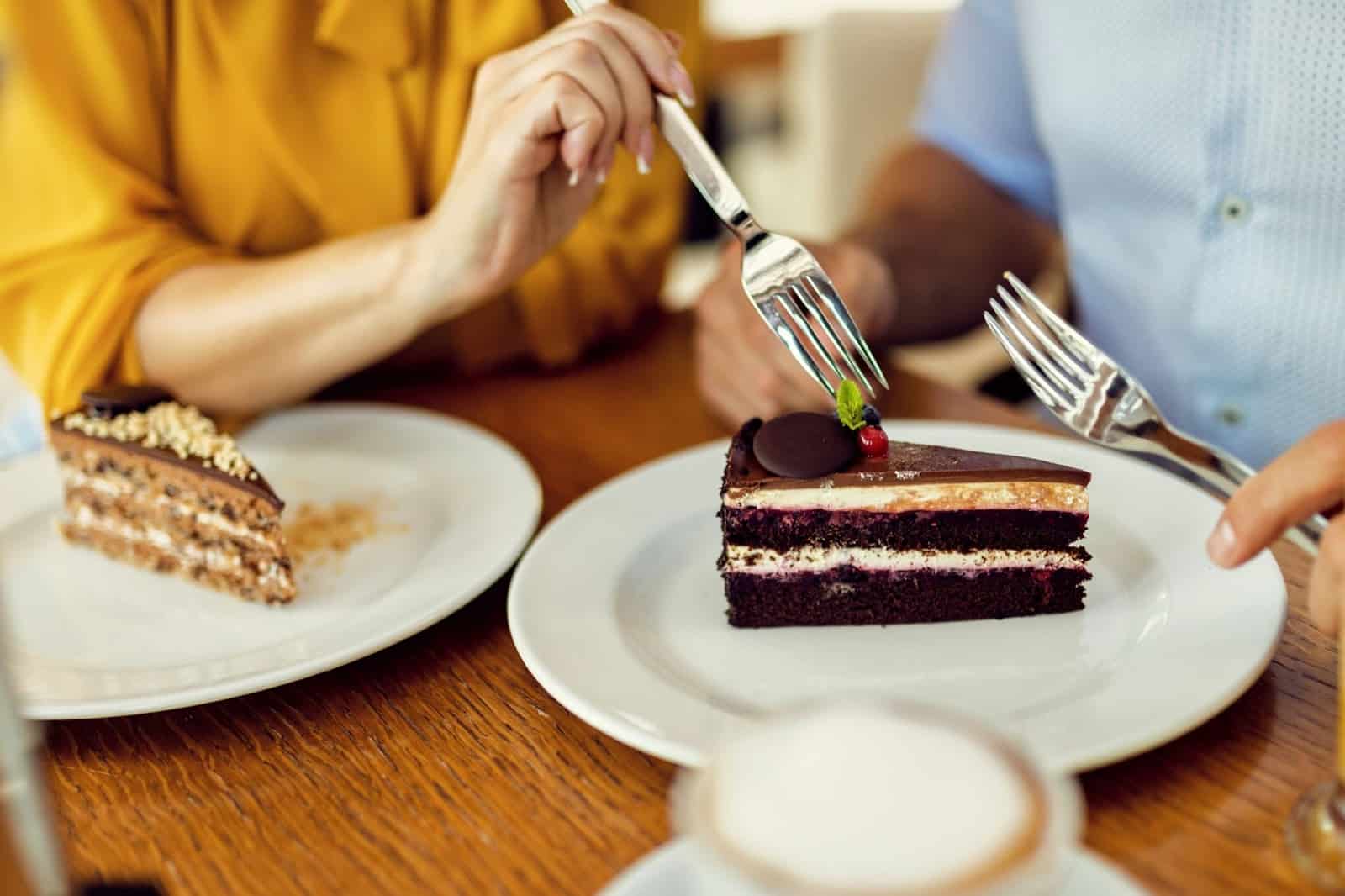 A picture of two person eating a cake.