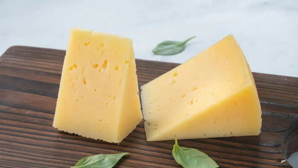 A pair of yellow cheese wedges on a wooden board.