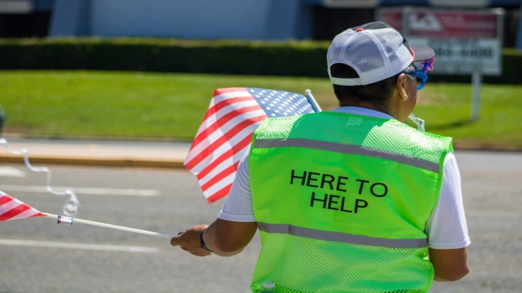 A volunteer wearing a “here to serve” vest