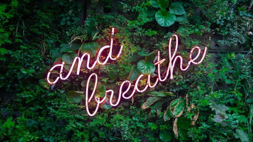 A neon light saying “and breathe”