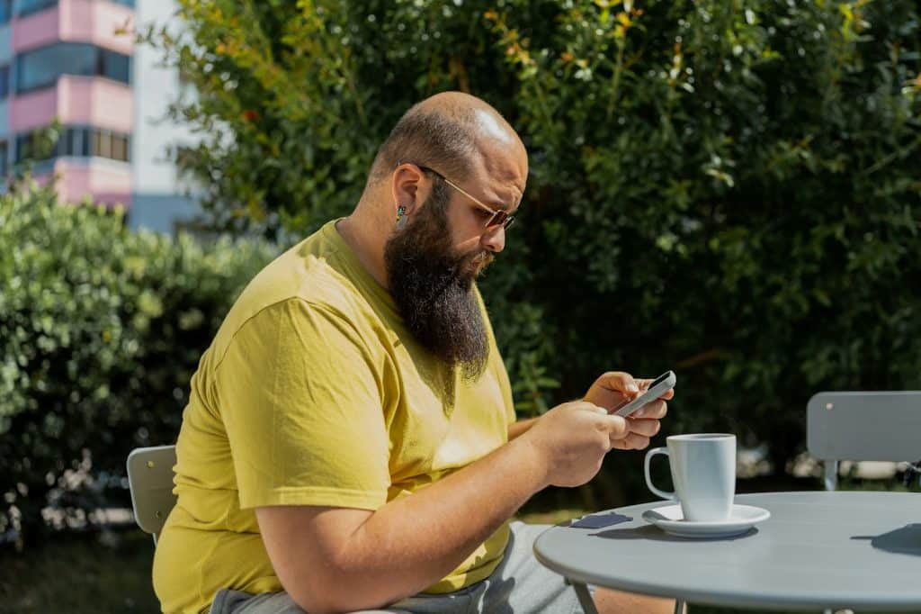 A man having a coffee and using a mobile phone