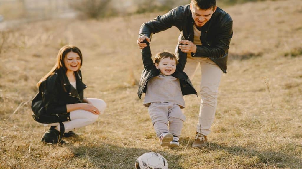 A couple playing soccer with their baby.
