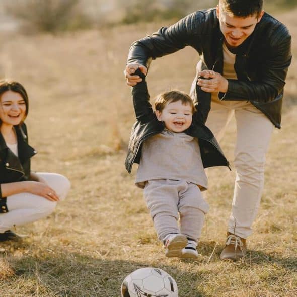 A couple playing soccer with their baby.