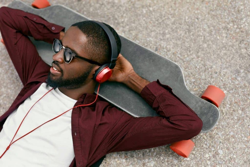 A man laying at the skateboard while listening to music
