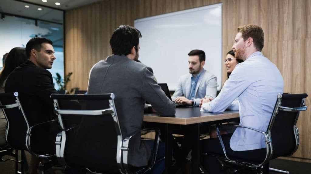 A group of five professionals are seated around a conference table in an office.