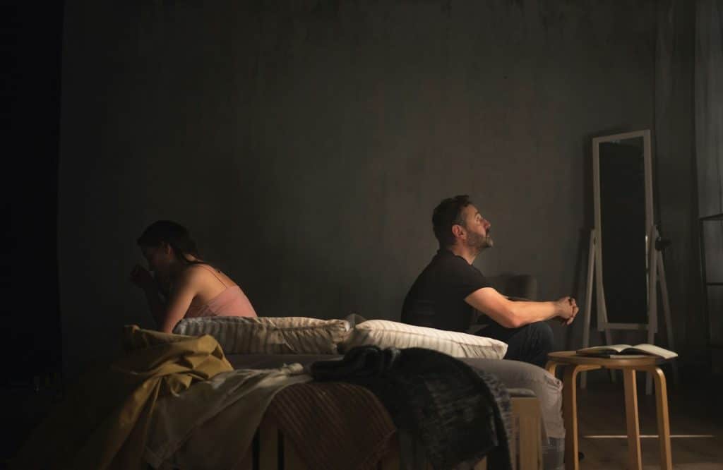 A man and woman sitting on the bed 