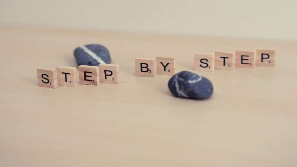 Wooden block letters spelling out “step by step”.
