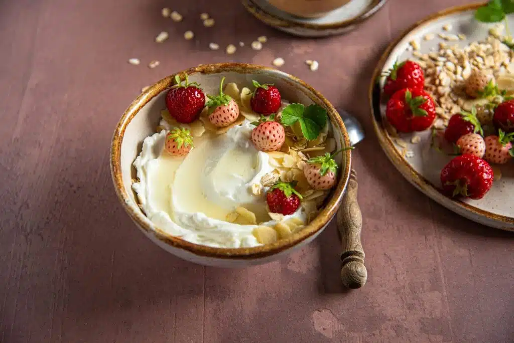 A plain yogurt with strawberries on side.