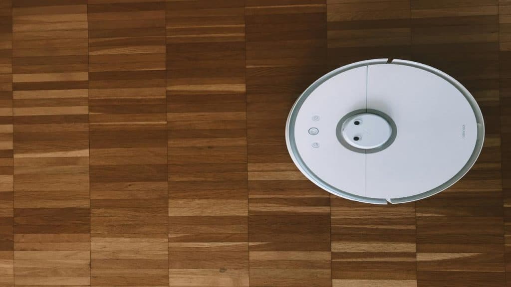 A white robot vacuum cleaner on a wooden floor.
