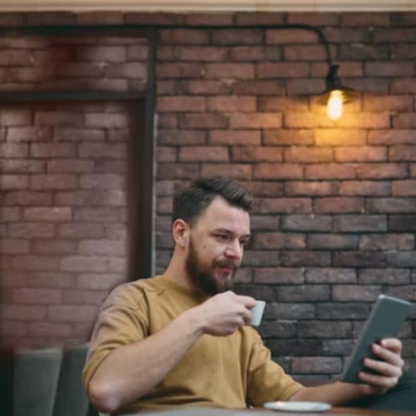 Man using a dating app on his phone while seated at a café table.
