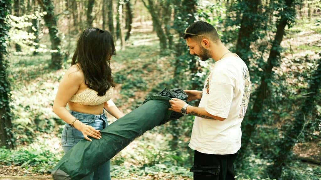 A man helping a woman set up a tent.
