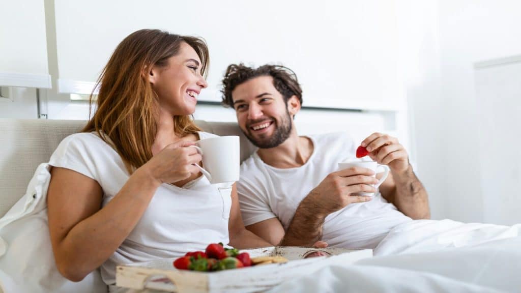 A man and a woman having breakfast in bed.
