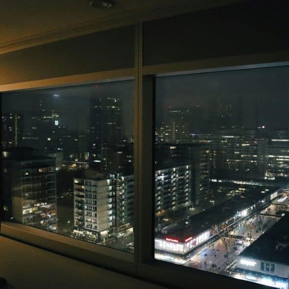 A man looking out the window from his apartment
