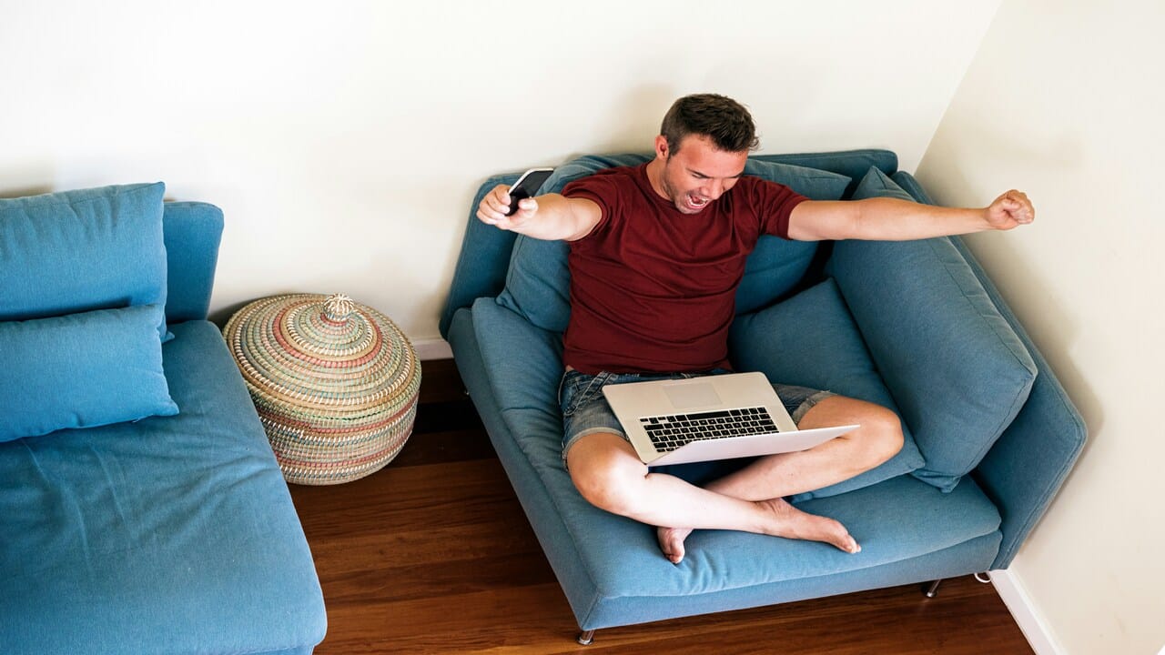 A man looking happy in front of his laptop.