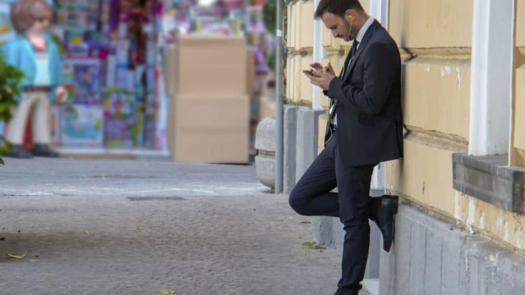 Confident man standing near the wall outside alone after reading a dating message.