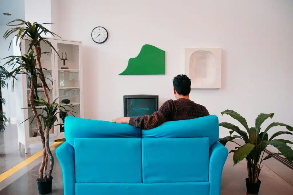 A picture of a man watching tv on a blue couch