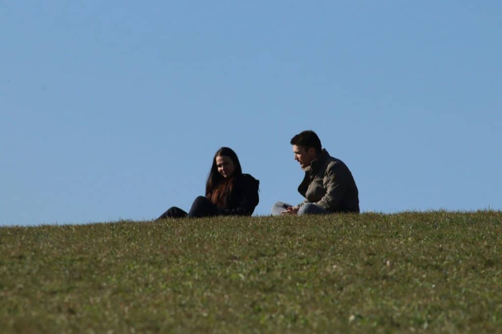 A couple talking while sitting at the grass.