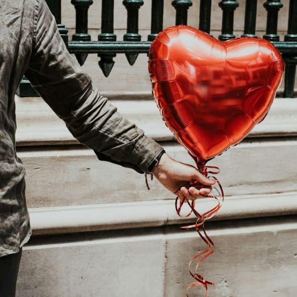 A person holding a heart balloon.