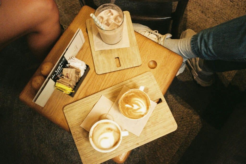 An iced coffee and two flavored coffee on a table.