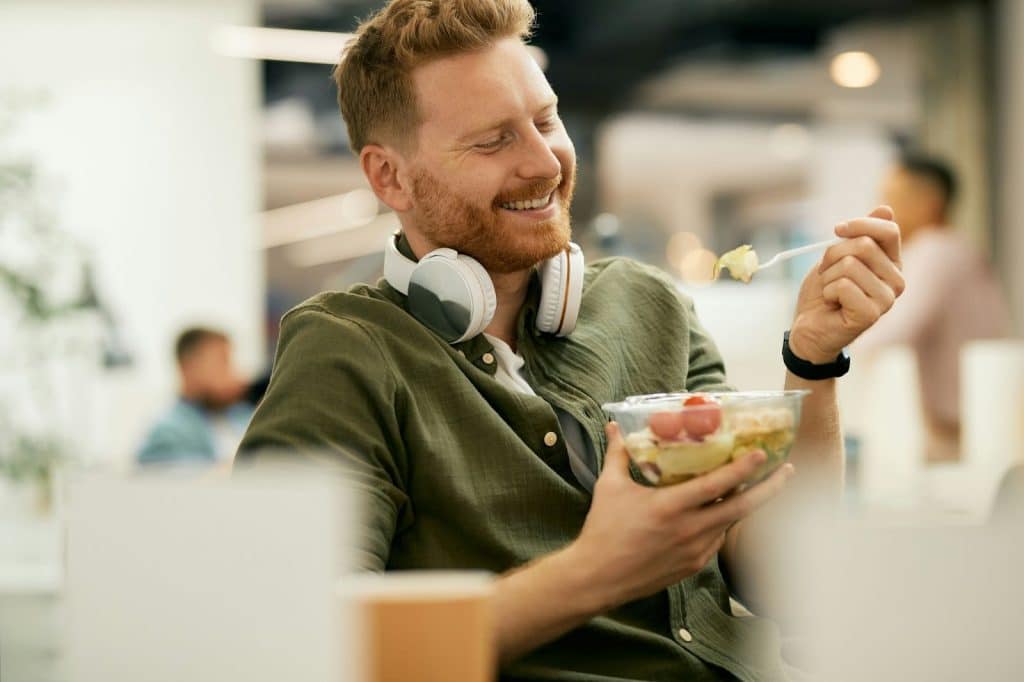 A Man eating his food while smiling.