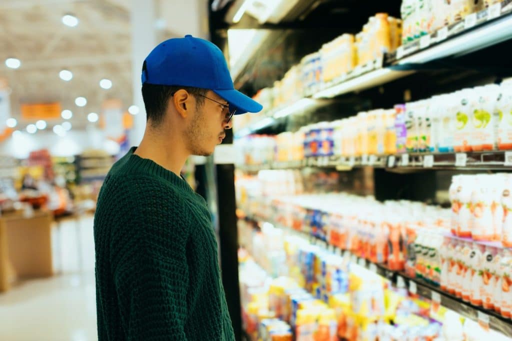 A man on a grocery store choosing food to buy.